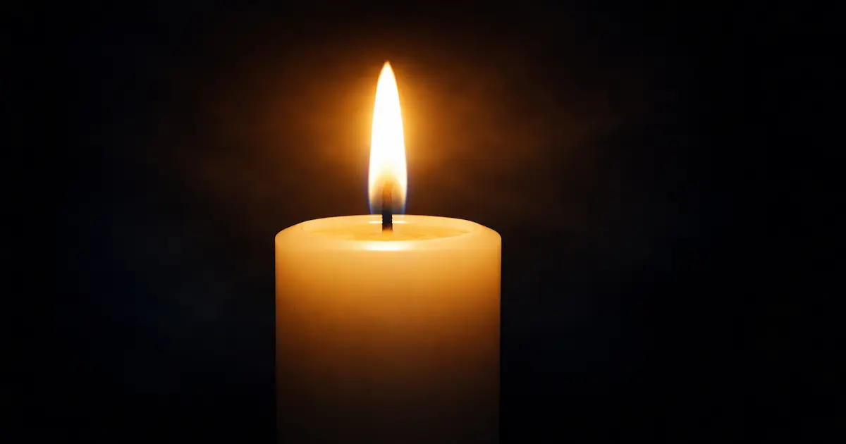 Vela encendida en la oscuridad con luz dorada que simboliza la vida que continúa después de la muerte